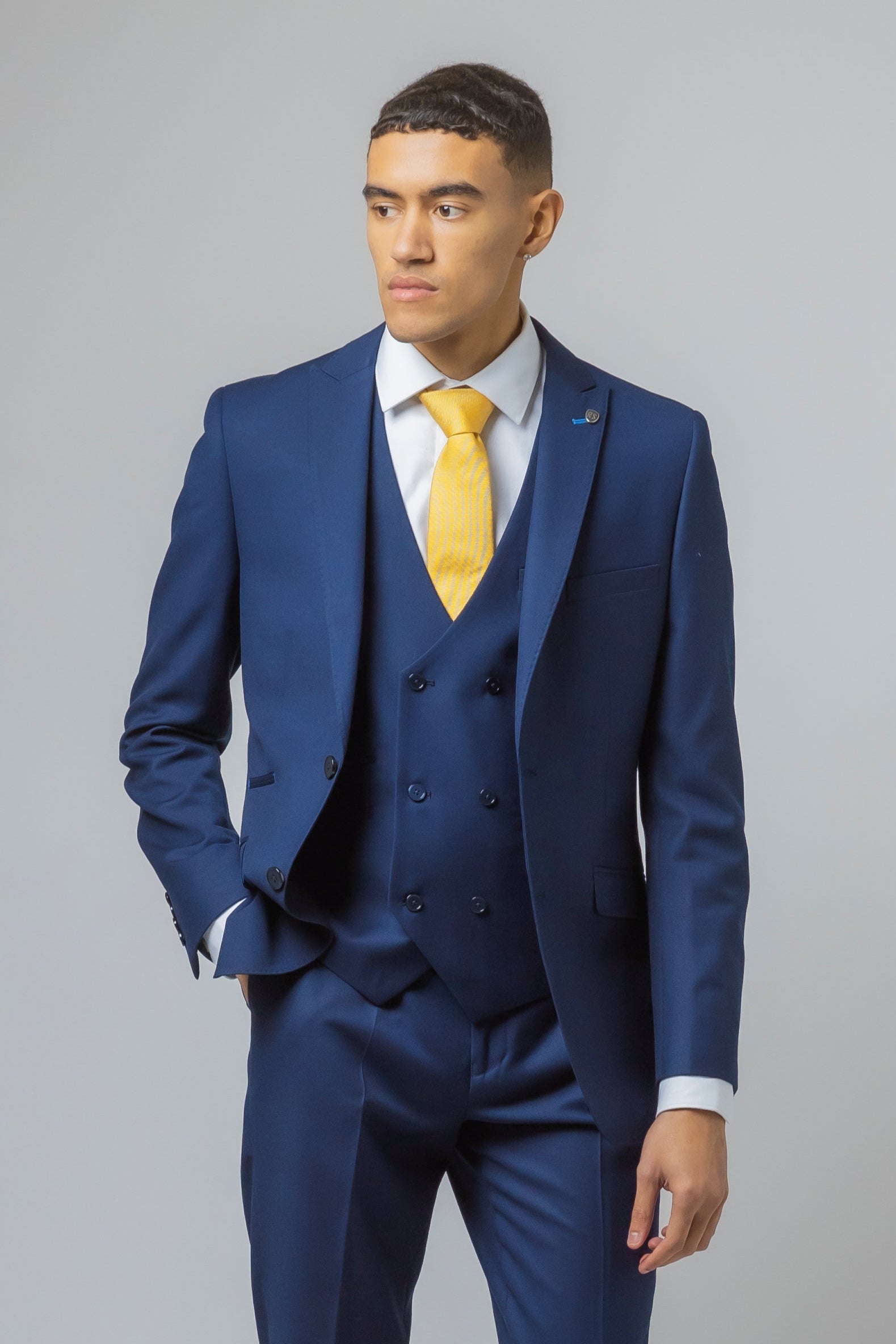 Man wearing a blue suit with a yellow tie on a gray background