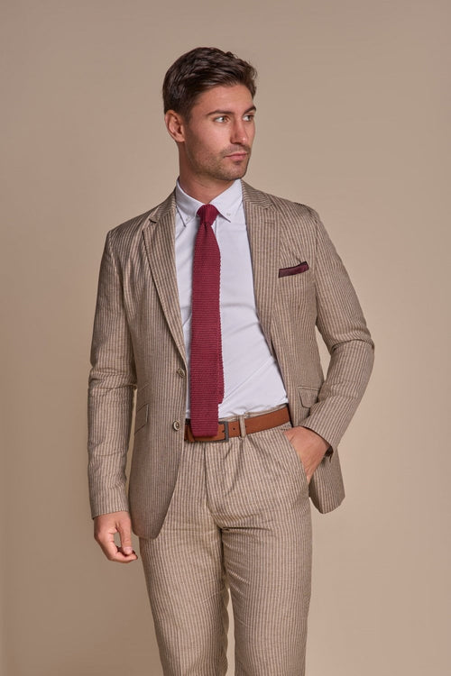 Man wearing a beige suit with a red tie and pocket square against a beige background
