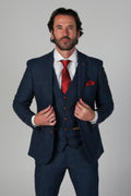 Man wearing a blue suit with a red tie and pocket square on a gray background