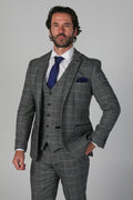 Man wearing a gray checkered suit with a blue tie on a gray background