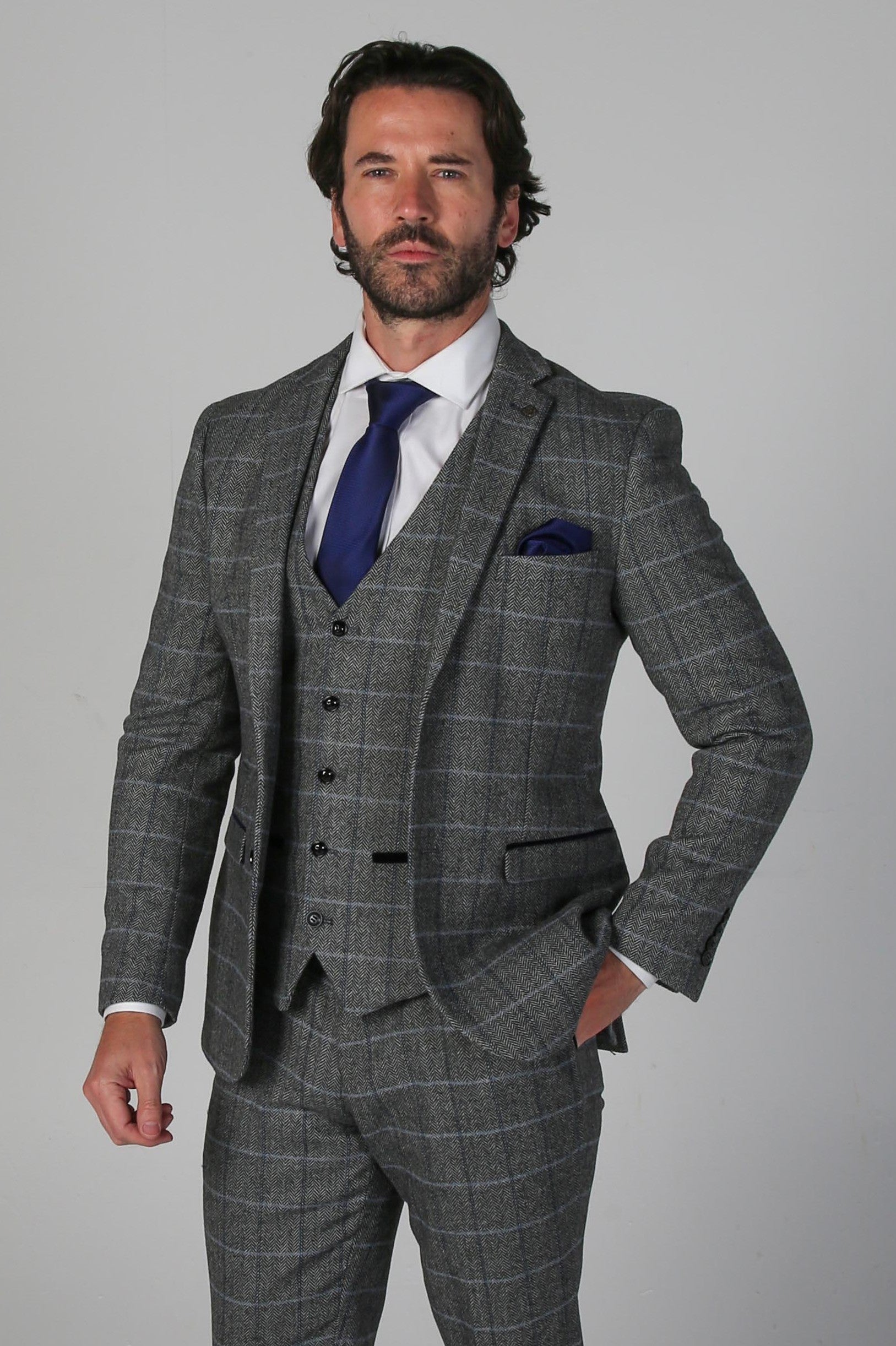 Man wearing a gray checkered suit with a blue tie on a gray background
