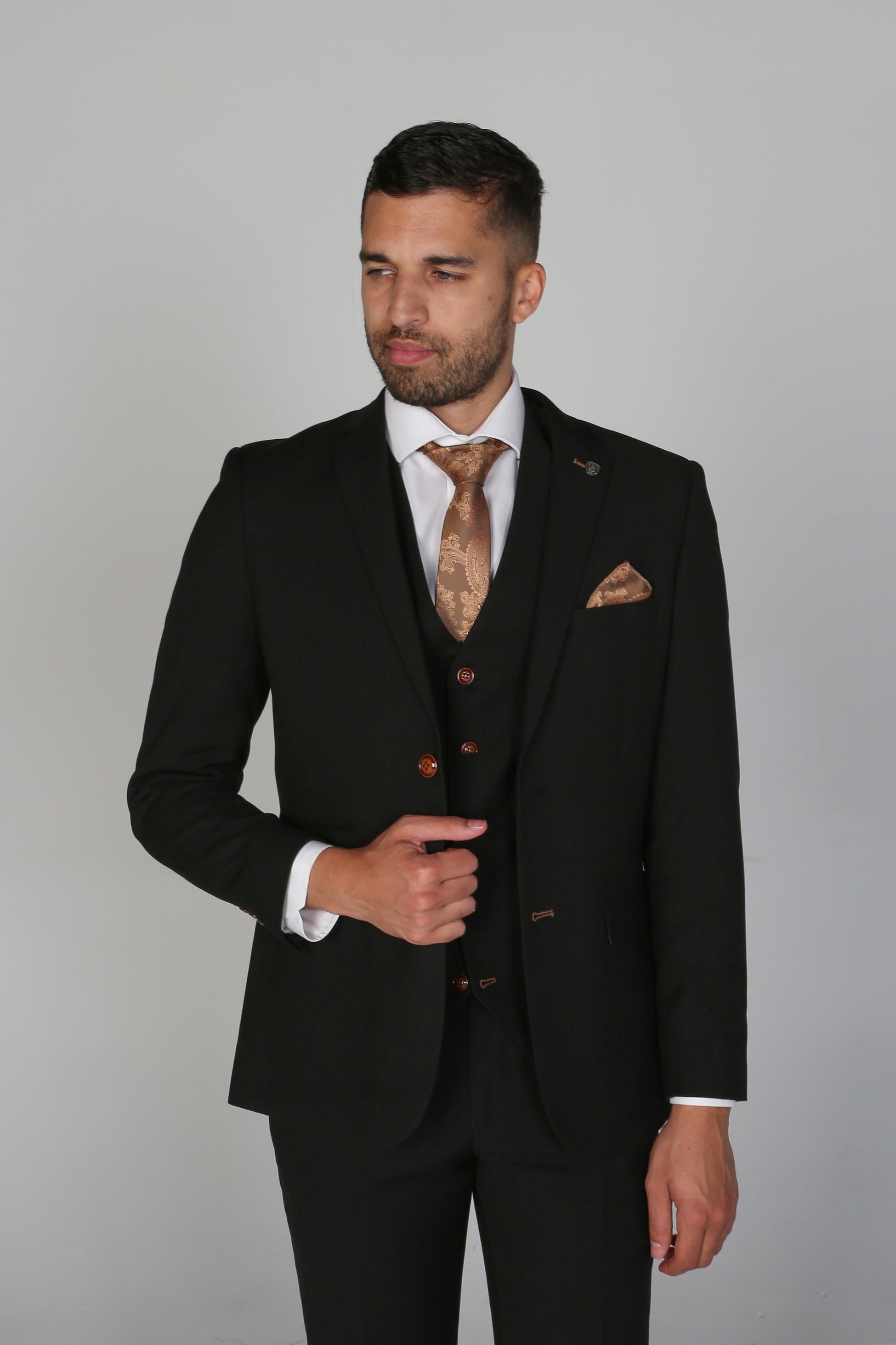 Man wearing a black suit with a patterned tie and pocket square on a gray background