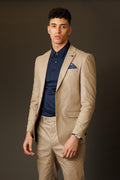 Man wearing a beige suit and navy shirt against a dark background