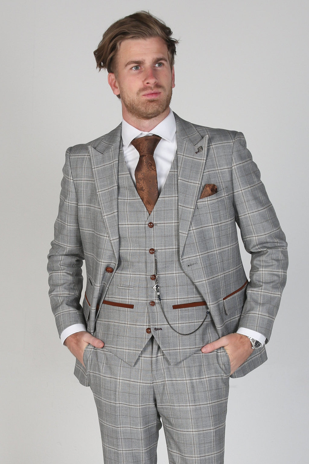 Man wearing a gray checkered suit with a white shirt and brown tie on a light gray background