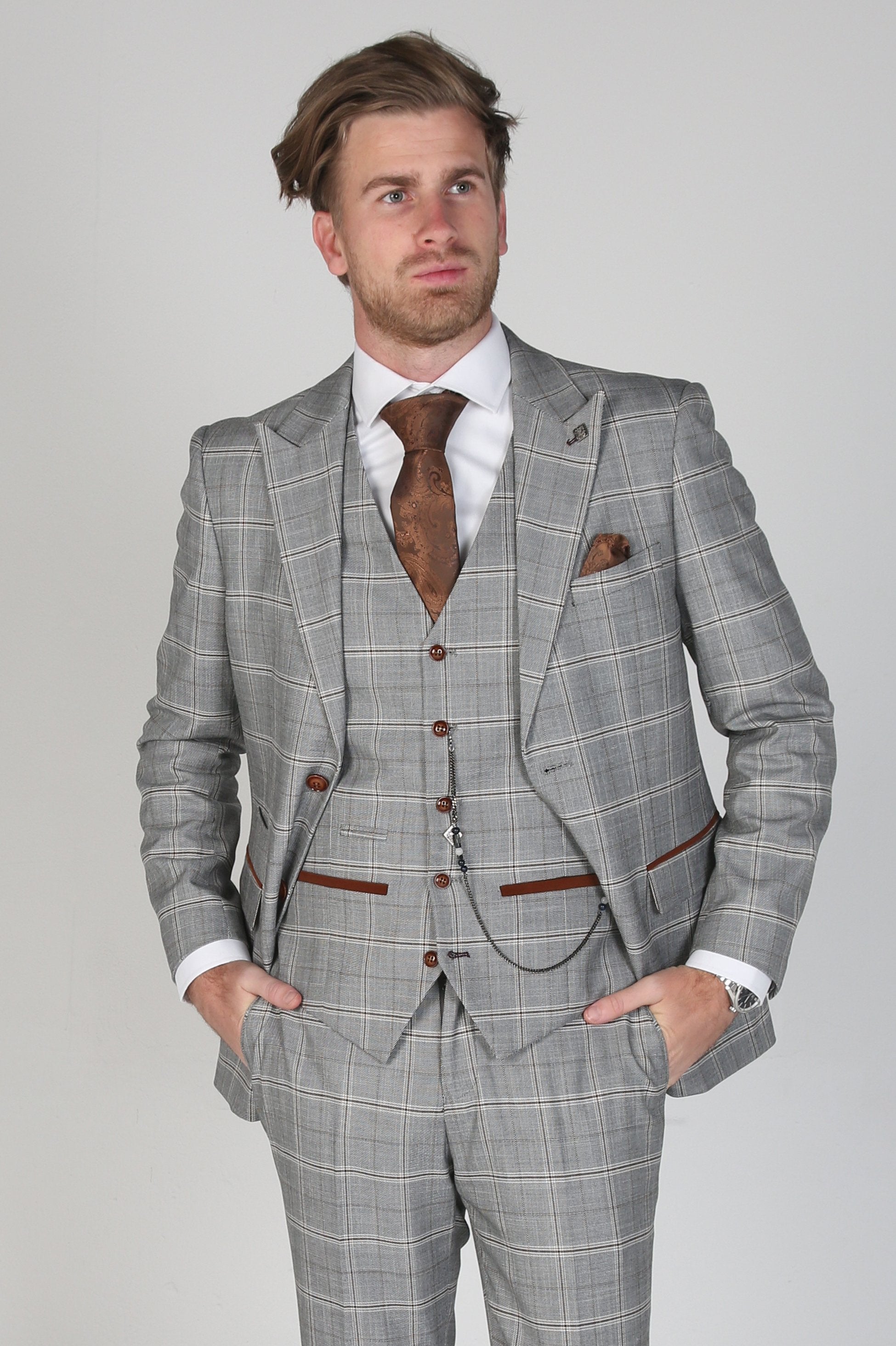 Man wearing a gray checkered suit with a white shirt and brown tie on a light gray background