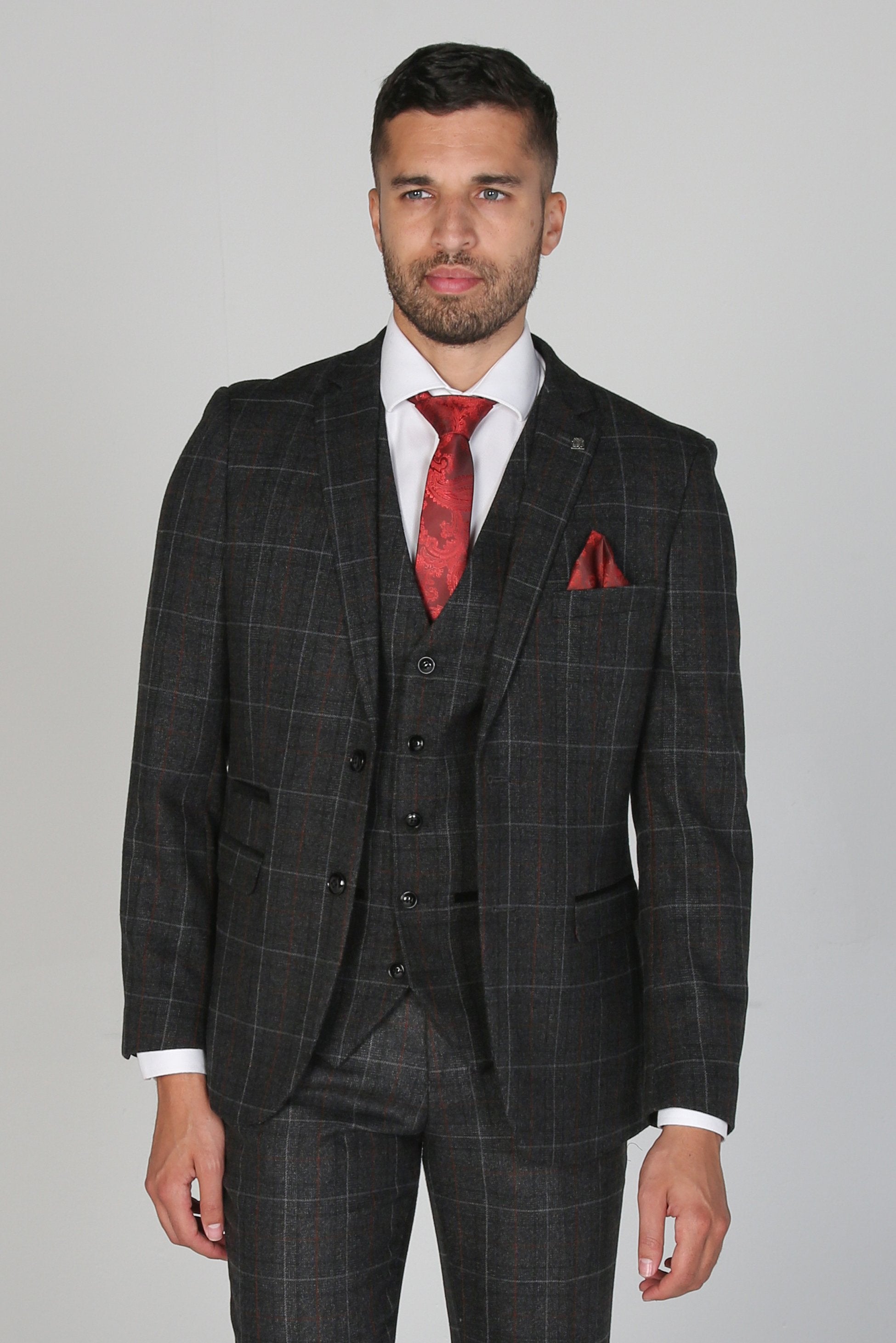 Man wearing a gray checkered suit with a red tie and pocket square on a gray background