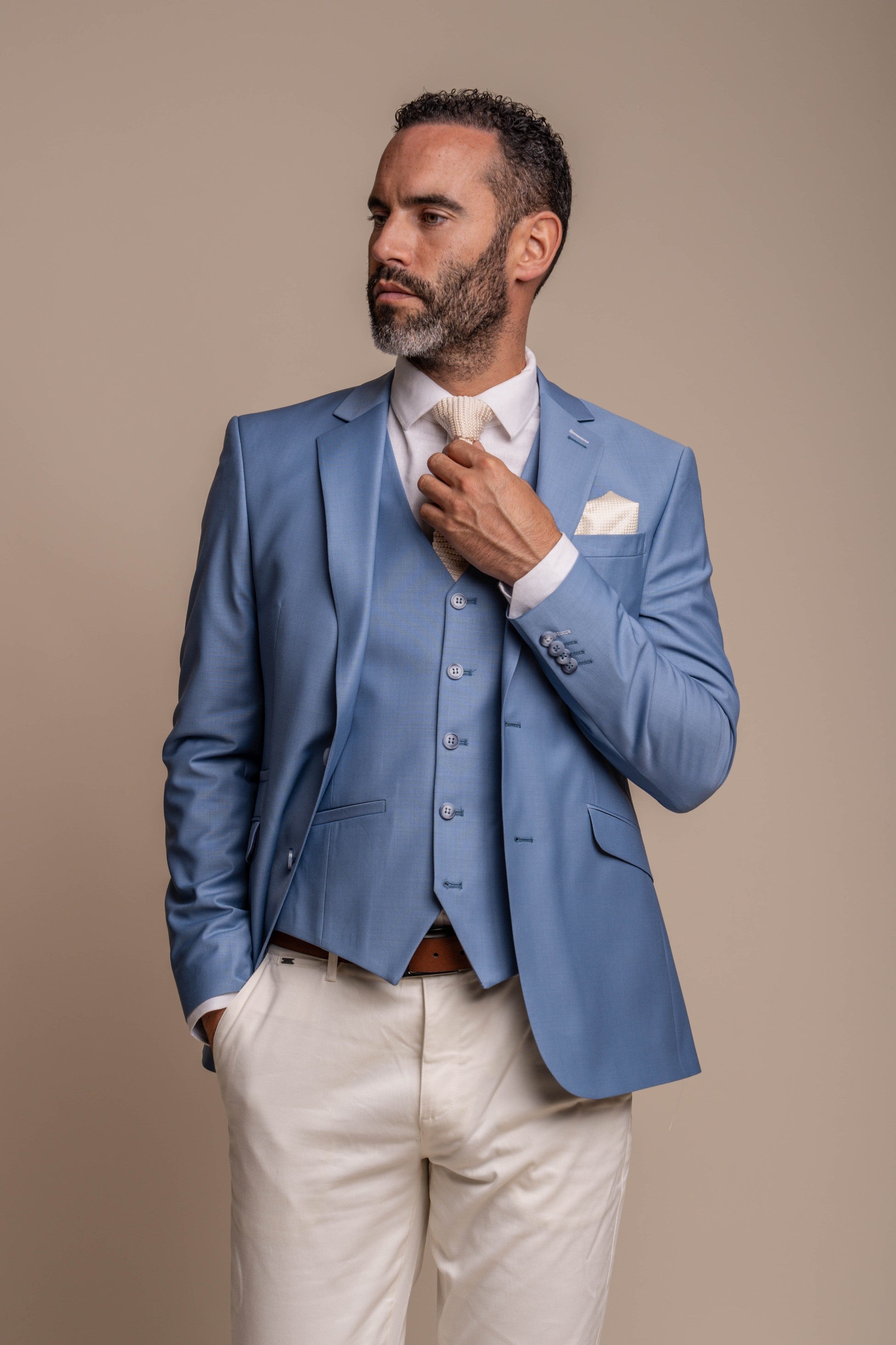 Man wearing a light blue suit with a white shirt on a beige background