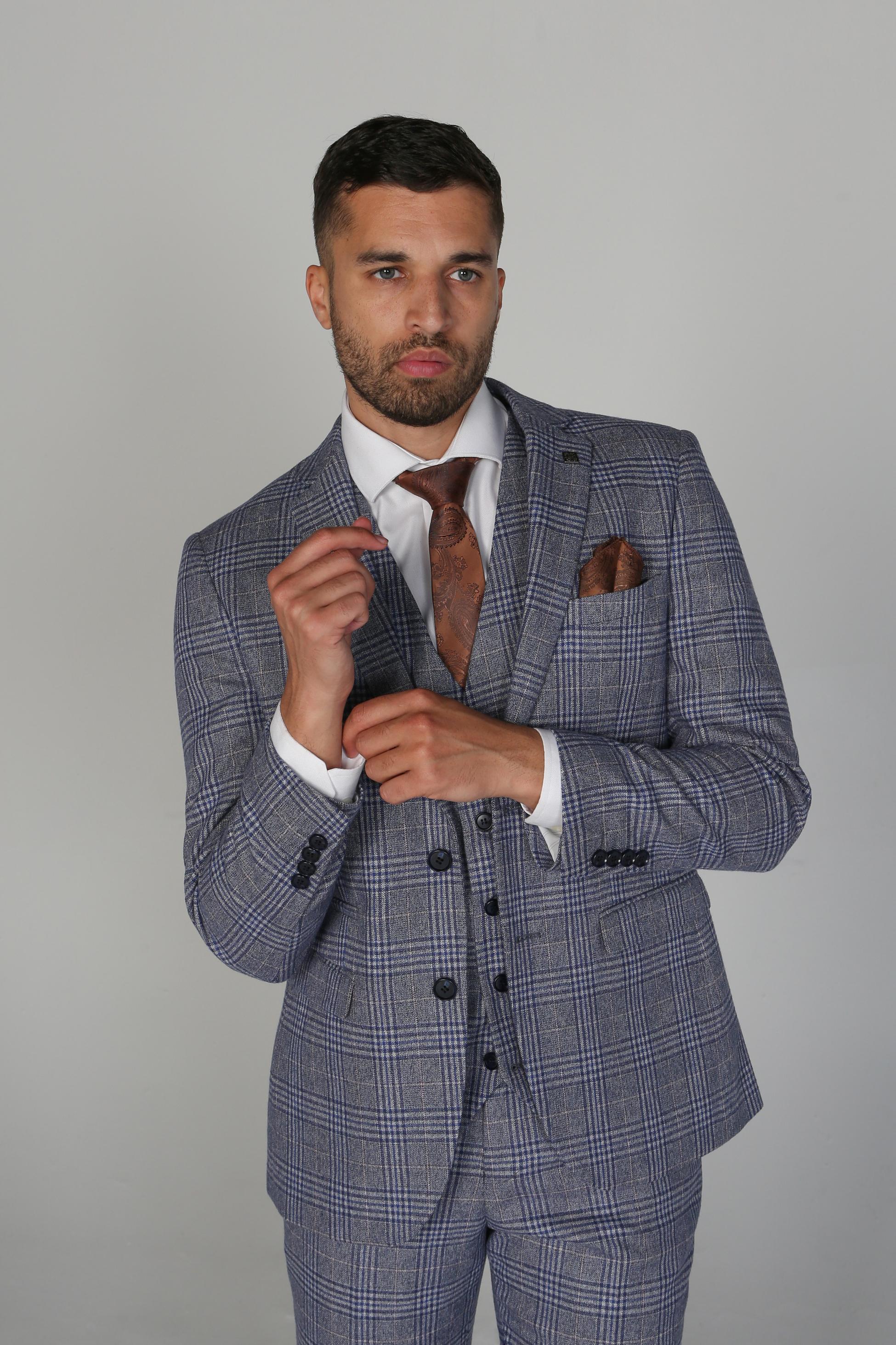 Man wearing a gray checkered suit with a brown tie and pocket square on a plain background