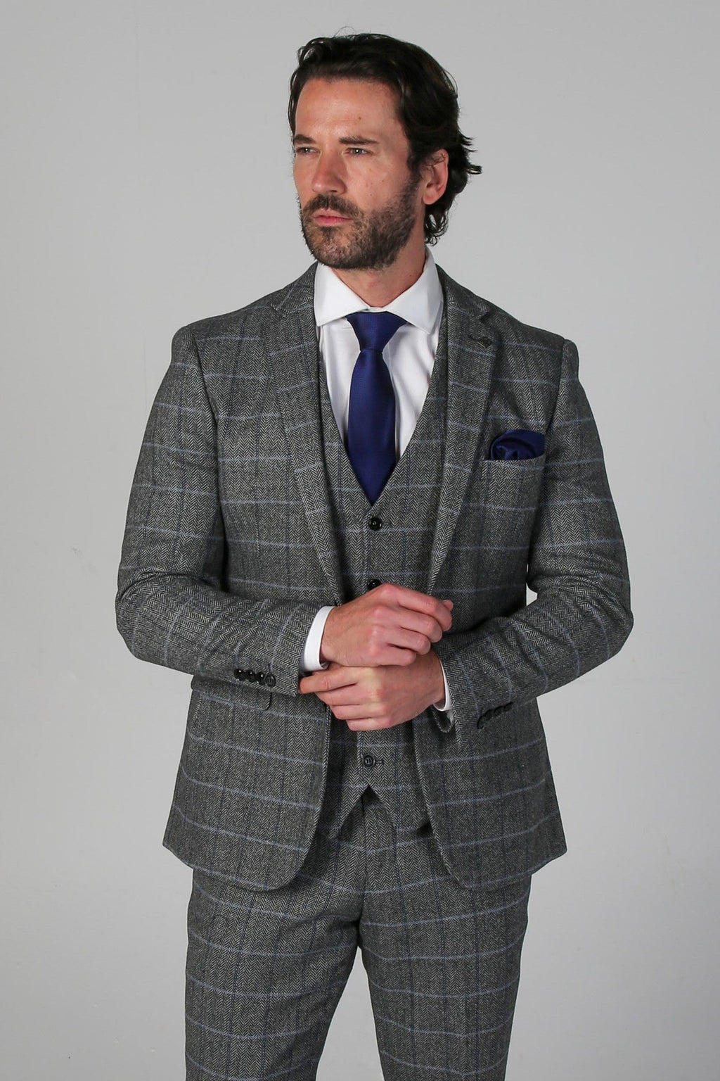 Man wearing a gray checkered suit with a blue tie on a gray background