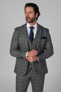 Man wearing a gray checkered suit with a blue tie on a gray background