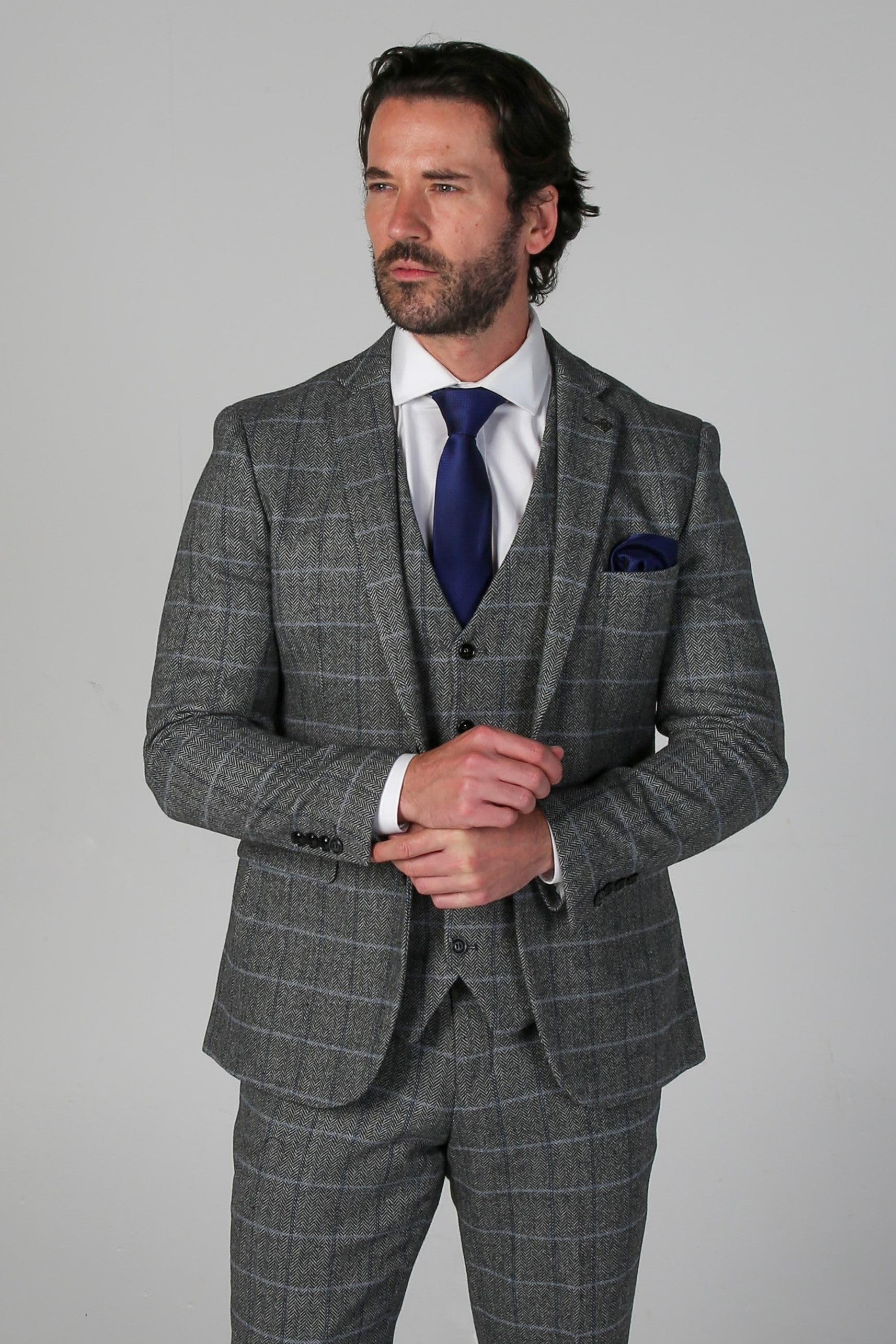 Man wearing a gray checkered suit with a blue tie on a gray background