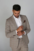 Man wearing a beige checkered suit with a white shirt on a gray background
