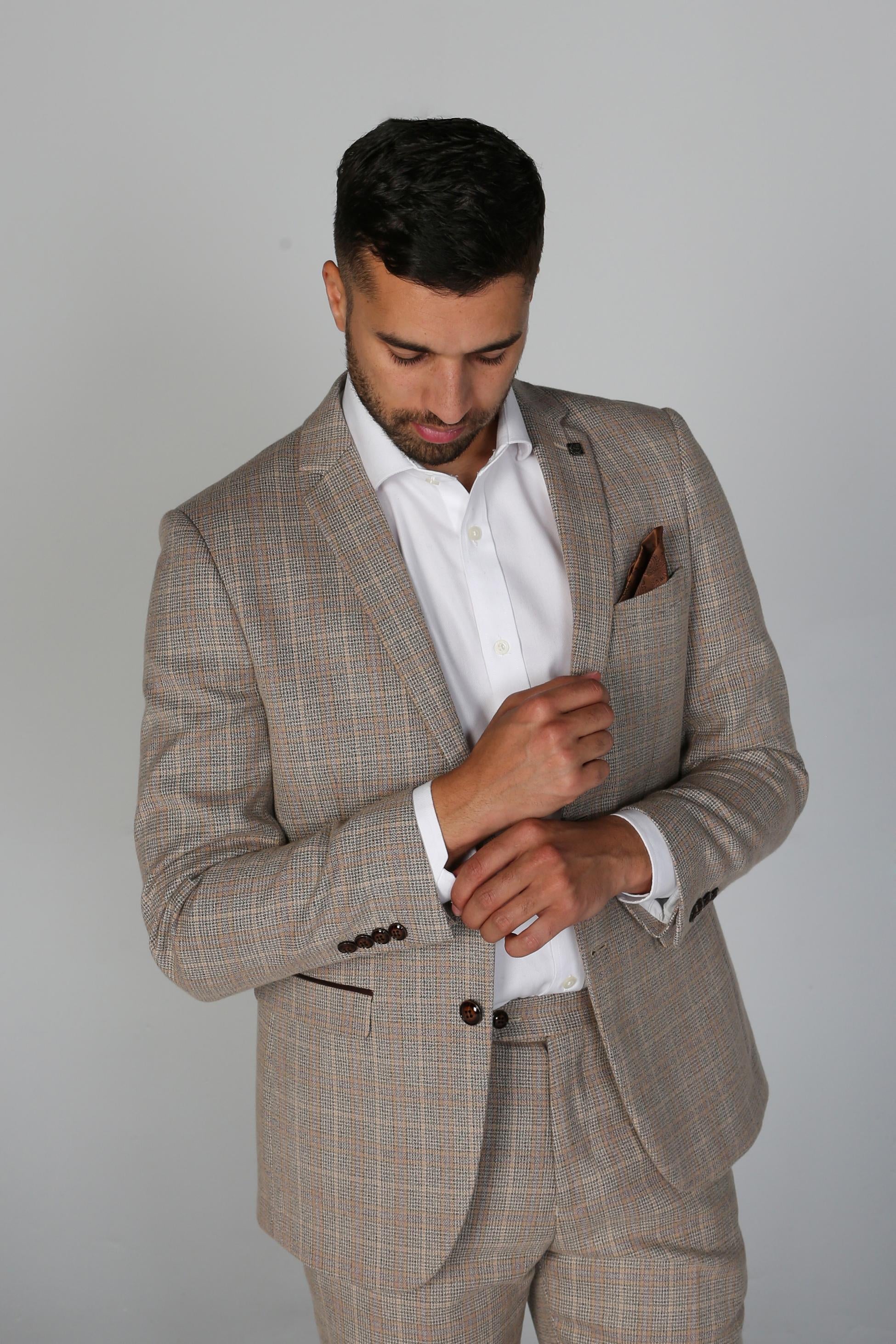 Man wearing a beige checkered suit with a white shirt on a gray background