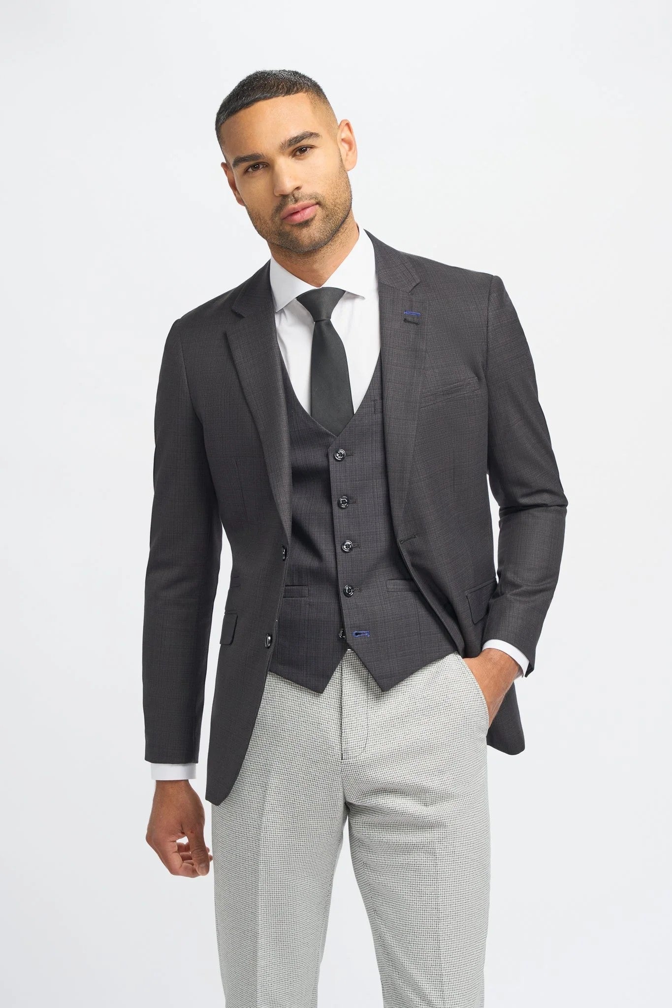 Man wearing a gray suit with a white shirt and tie on a light gray background