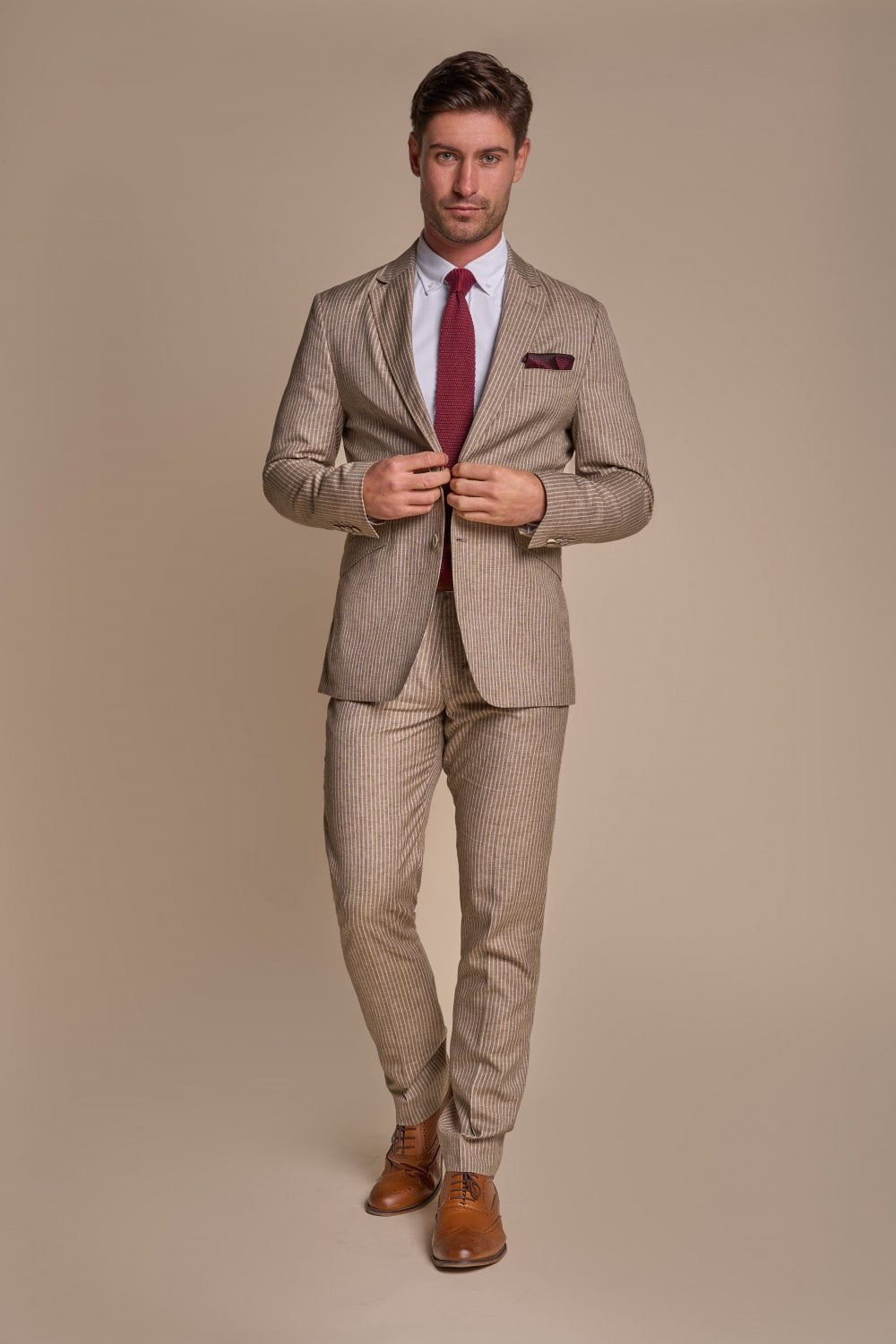 Man wearing a beige checkered suit with a red tie on a beige background