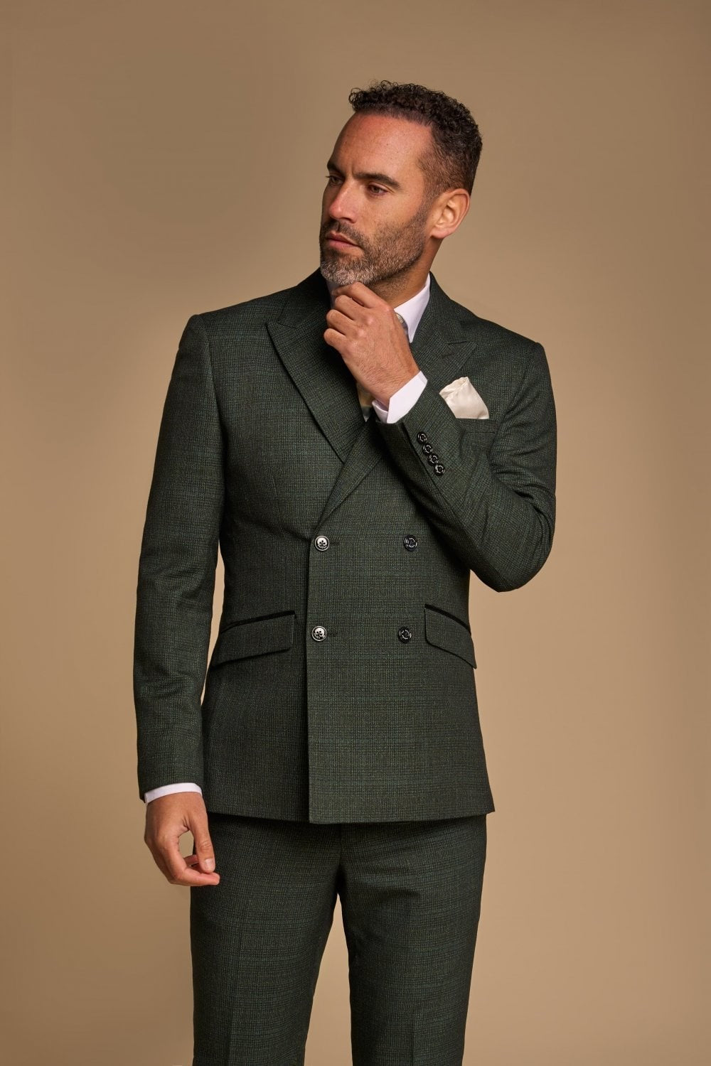 Man wearing a dark green suit with a beige background
