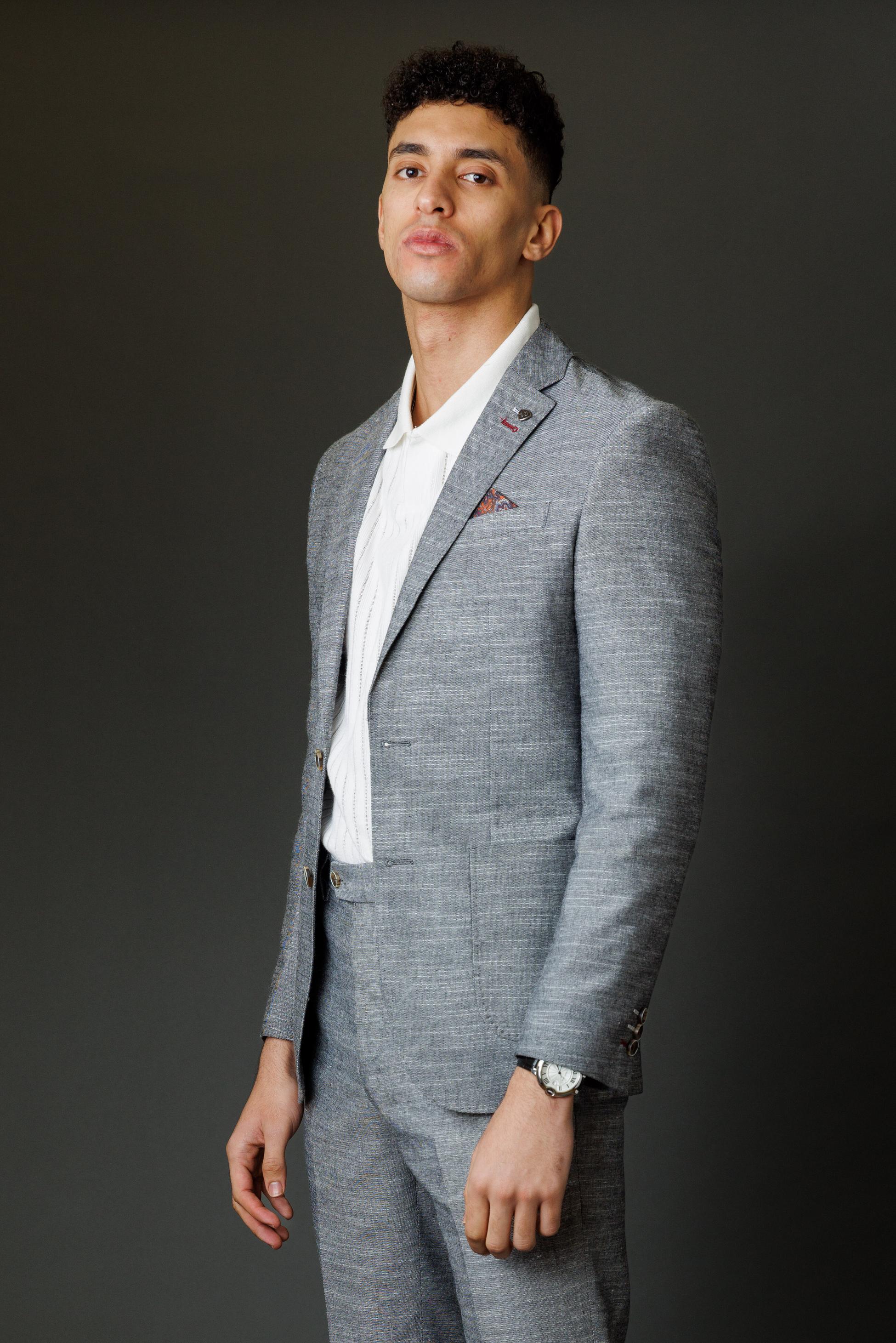Man wearing a gray suit and white shirt against a dark background